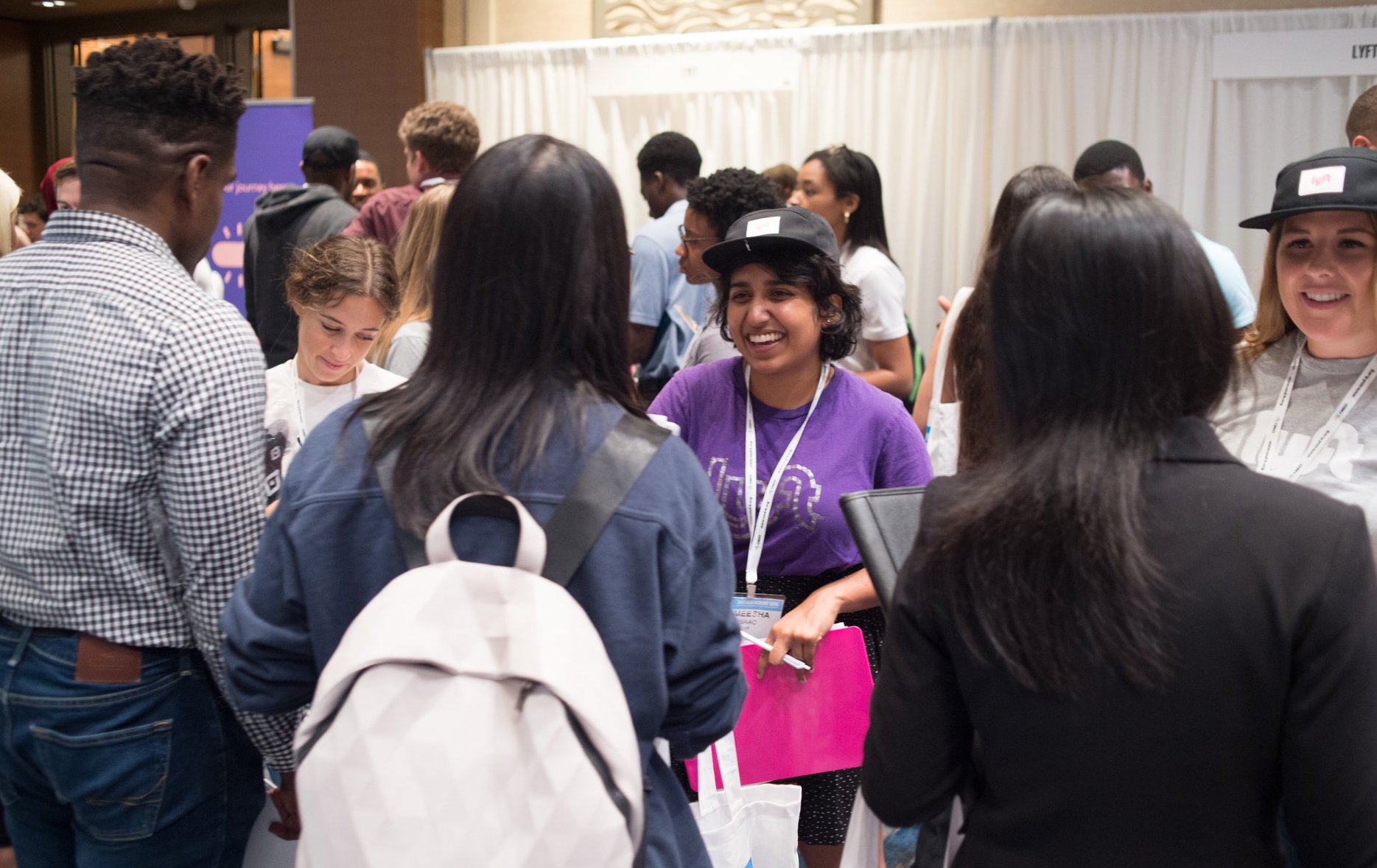Three conference attendees talking to three industry recruiters at Tapia 2019 Career Fair with other conference attendees in the background
